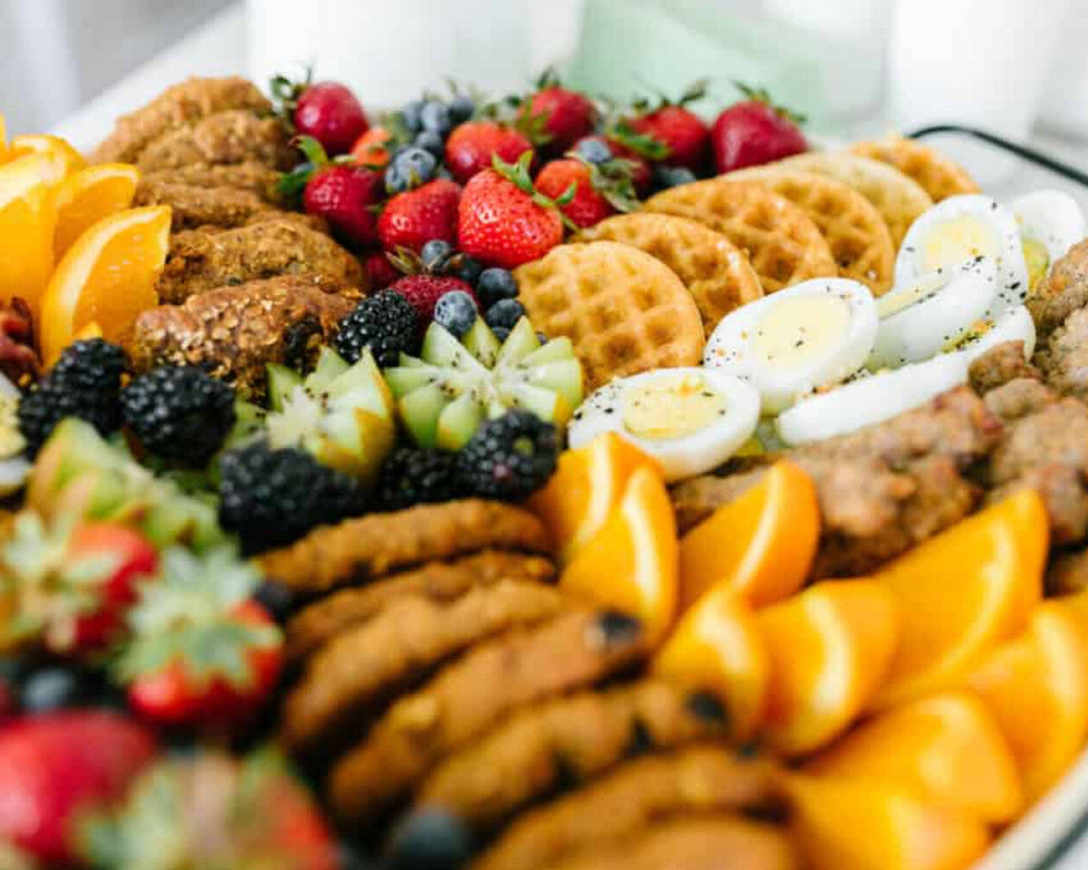 Breakfast items displayed in a buffet style consisting of bagels, cookies, fruit, healthy breakfast options.  