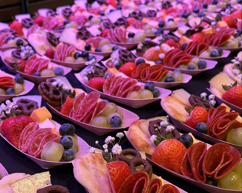 Customized charcuterie trays with meats, breads, fruits, and chocolate covered pretzels.  