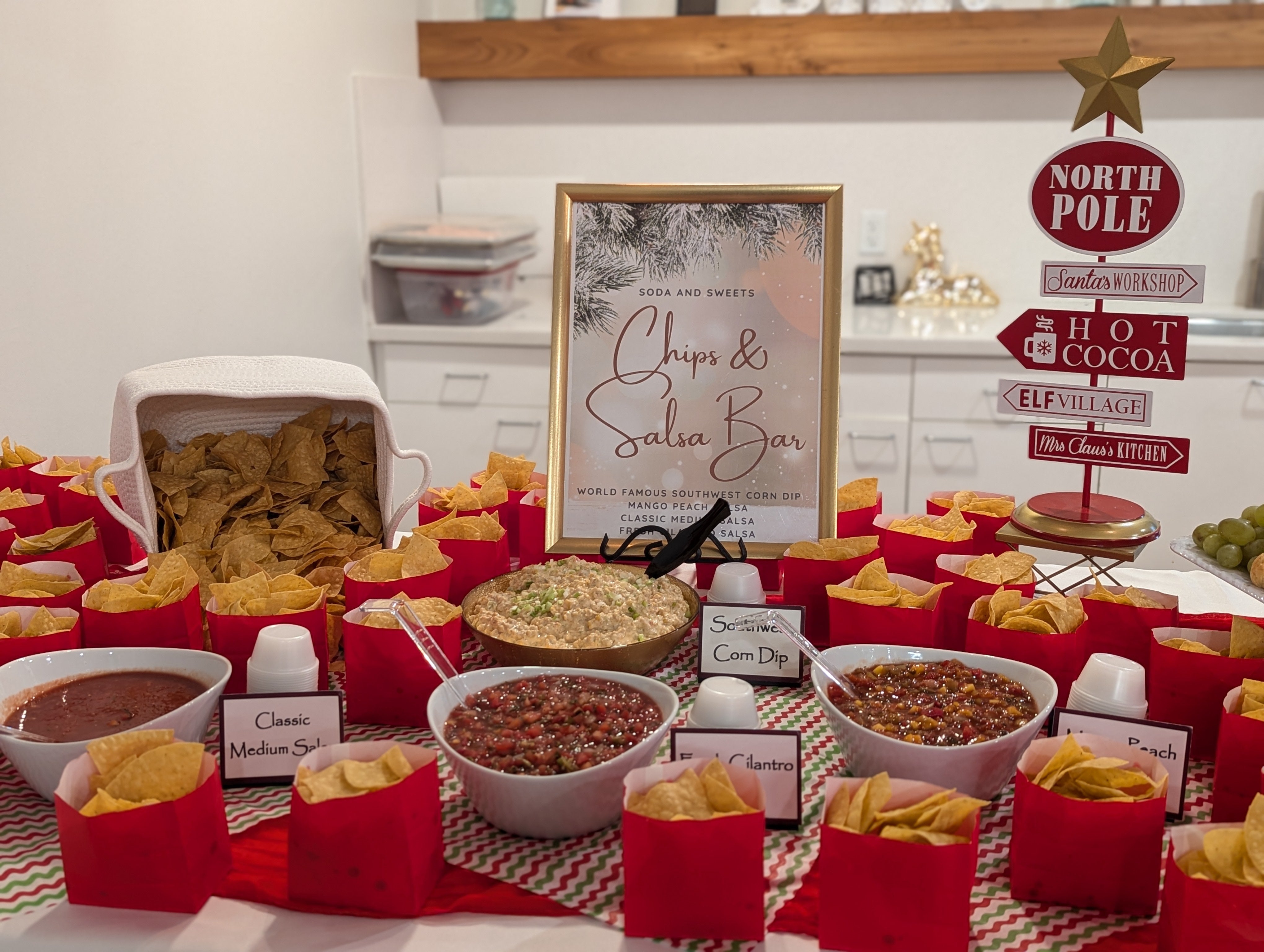 Chips and salsa displayed on a countertop.  Three different types of salsa and a southwest corn dip are available.  Bags of chips and a large basket of chips are shown.  