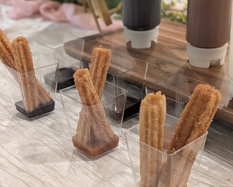 Small clear cups of churros with dipping sauces.  