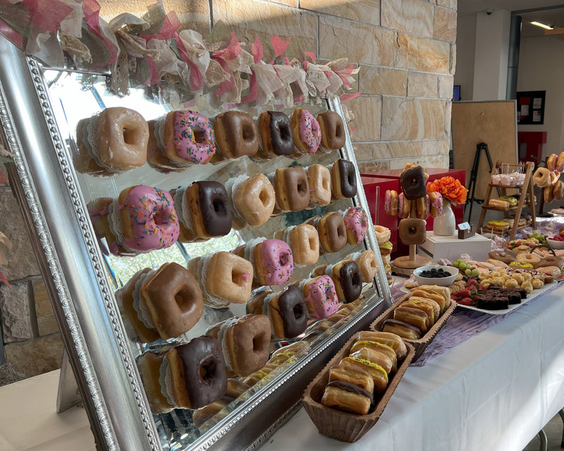 Donut display with various flavors on a table in a casual setting.