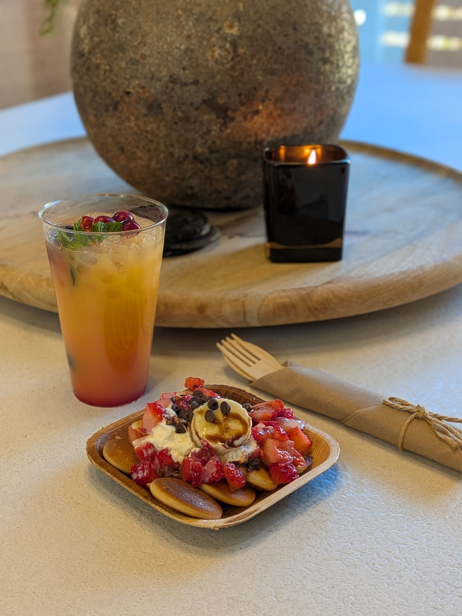 Small plate of pancakes with fruit and a mocktail (glass of juice) on a table.