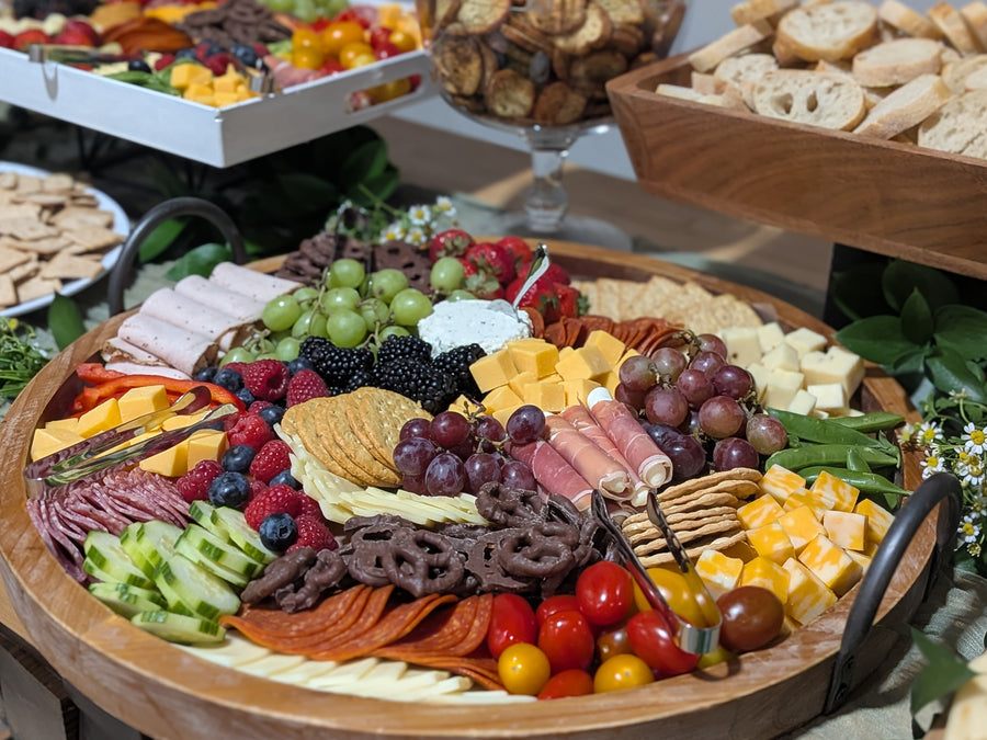 Assorted food platter with fruits, cheeses, and crackers on a table.