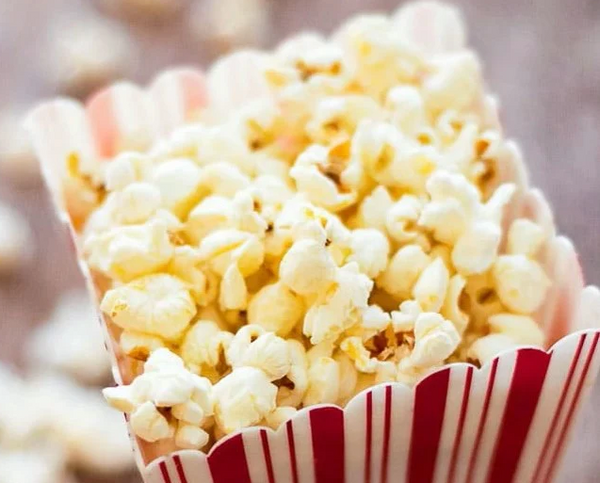 Large box of freshly popped popcorn, buttery fresh in a traditional red and white popcorn box.  