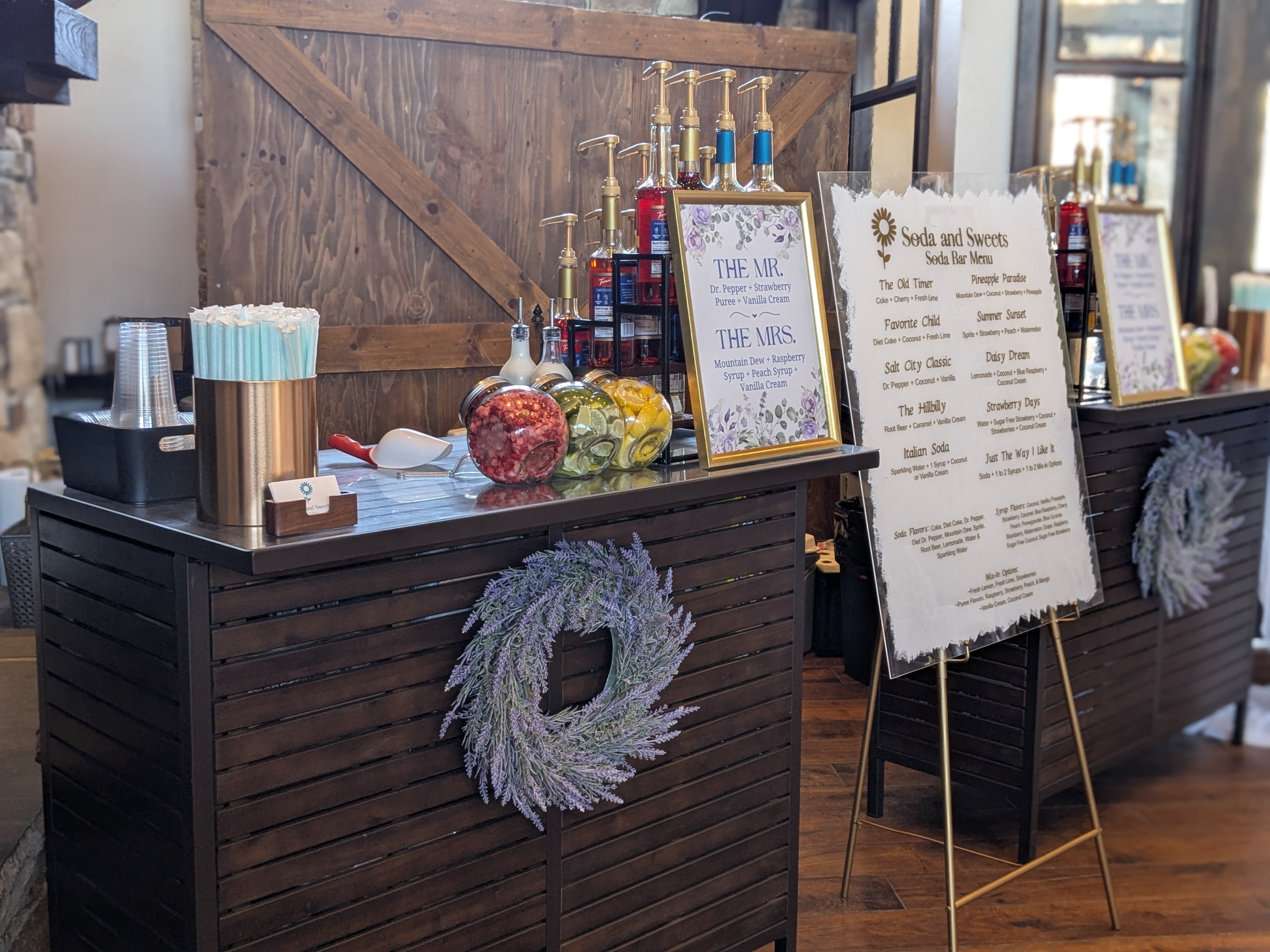 Two large soda bars for serving flavored sodas.  A large menu with flavored soda options is in the middle.  Lemons, limes, strawberries, and syrups are displayed for patrons to choose from.  