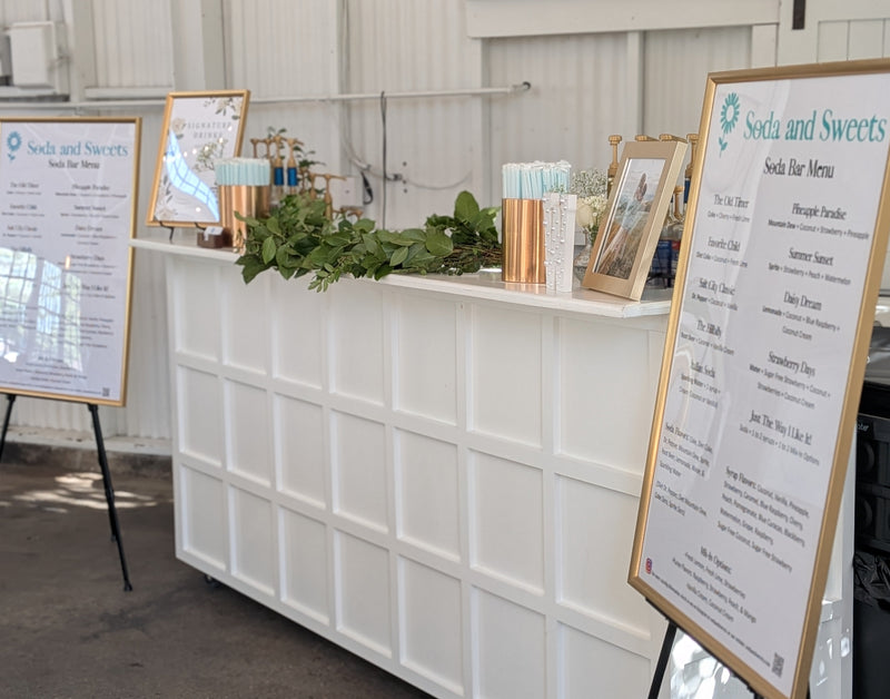 Soda bar.  Serving bar setup with flavored soda drink menus, cups, and decorative wreath.