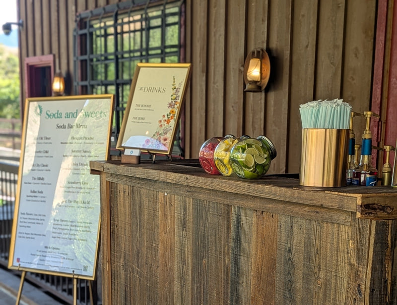 Utah soda bar.  Outdoor bar setup with flavored soda drink menus, cups, and decorative wreath.