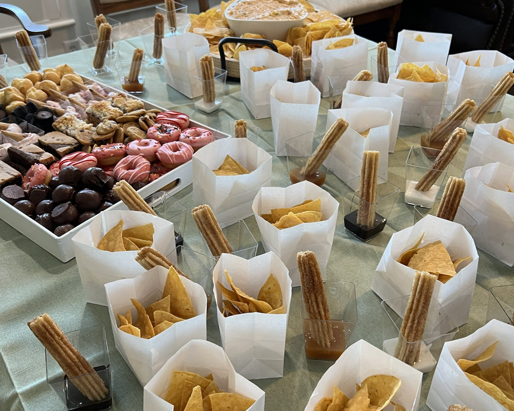 Table with various food items in white containers on a light green tablecloth.